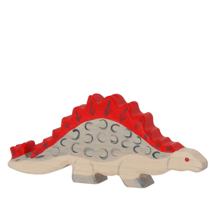 A wooden toy Stegosaurus dinosaur with a natural light wood body, a bright red back and spikes, and dark gray engraved details, shown on a plain white background.