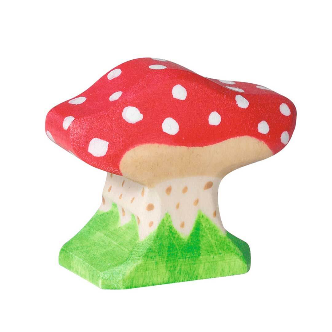 Painted wooden toy mushroom figurine with a red cap, white spots, beige stem, and green base on a white background.