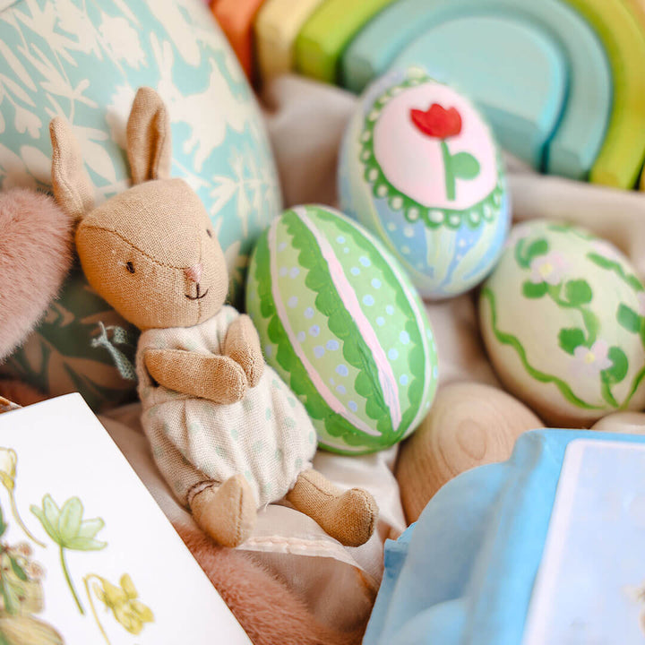 Decorative Easter eggs with a plush rabbit toy on a soft fabric background