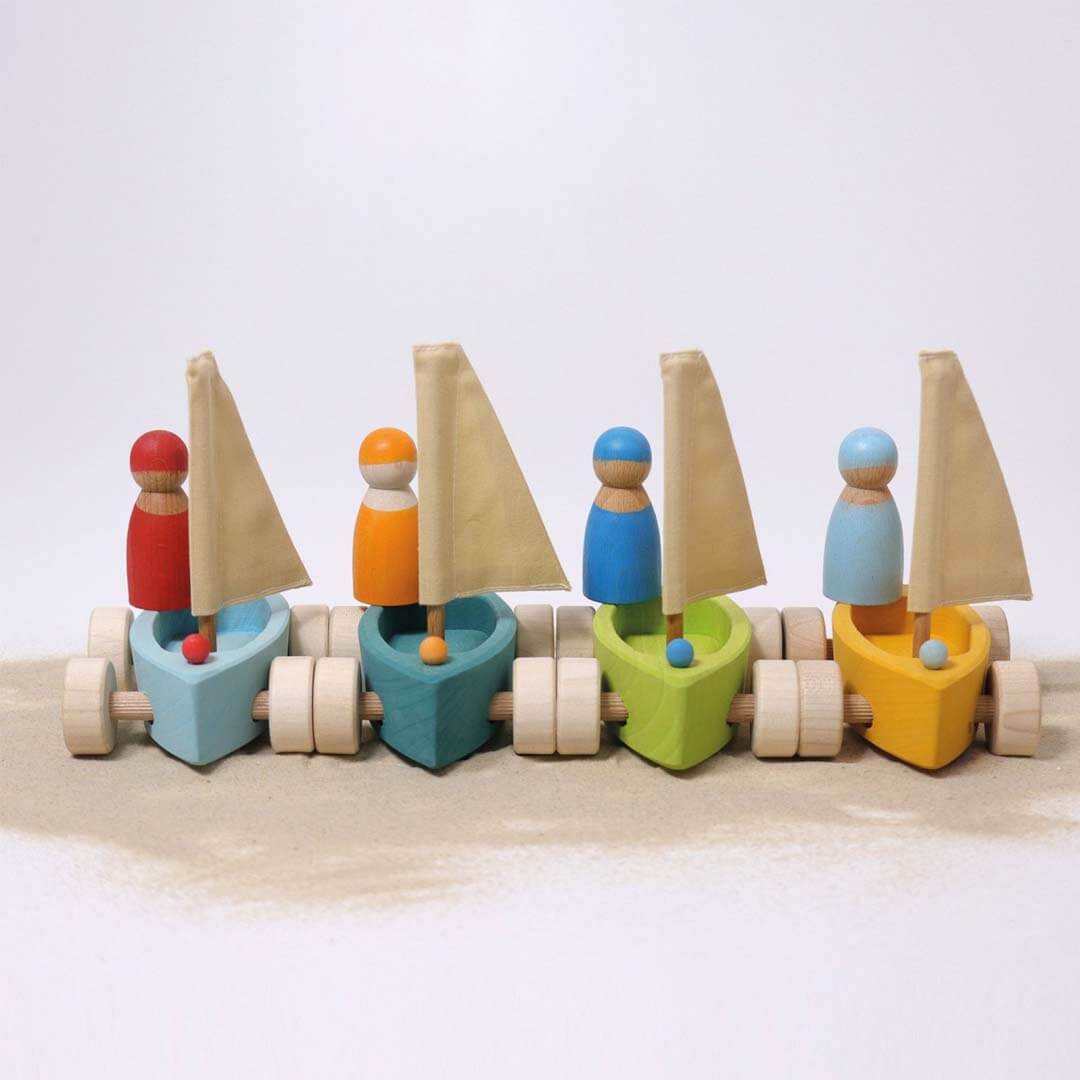Set of colorful wooden sailboats with figures on a white background