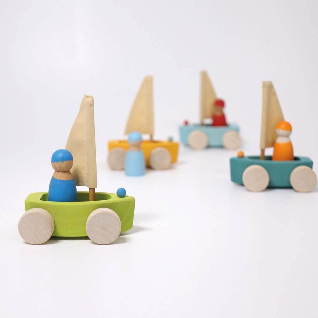 Set of colorful wooden toy sailboats on a white background