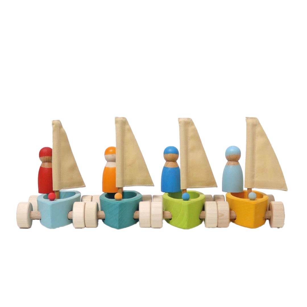 Set of colorful toy sailboats with peg people on a white background