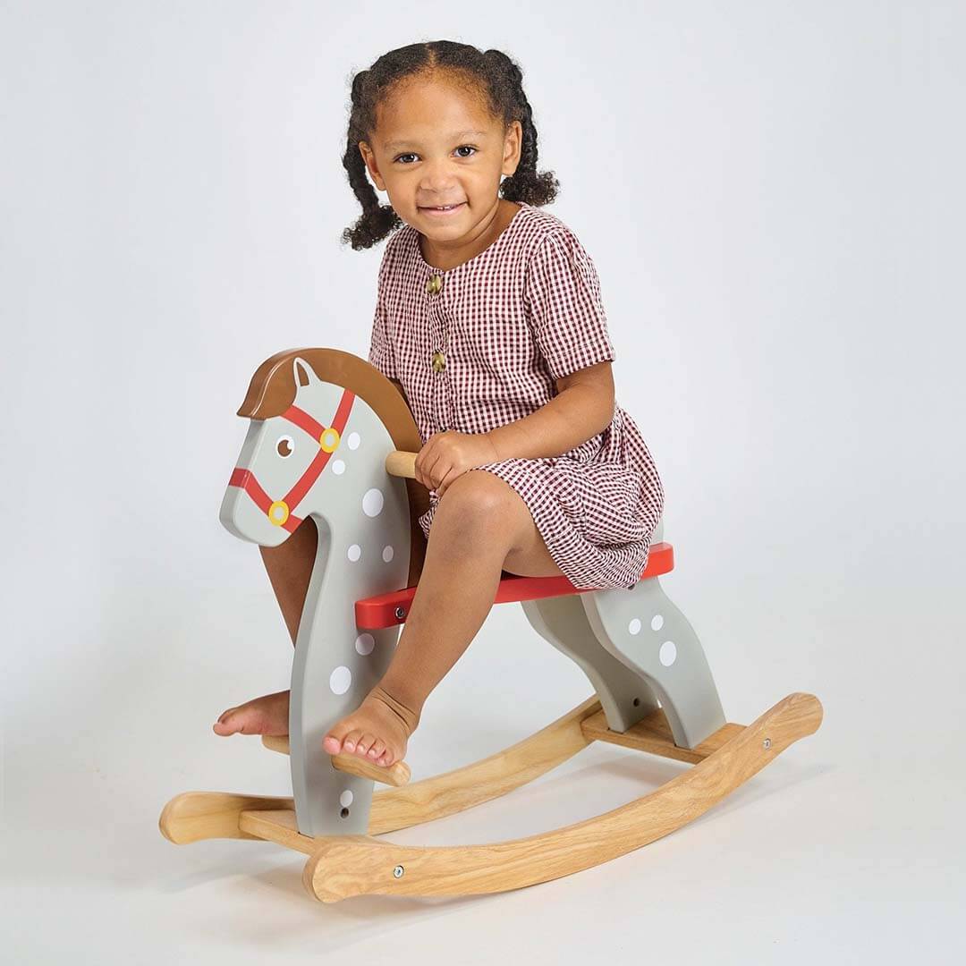 Child sitting on a wooden rocking horse against a white background