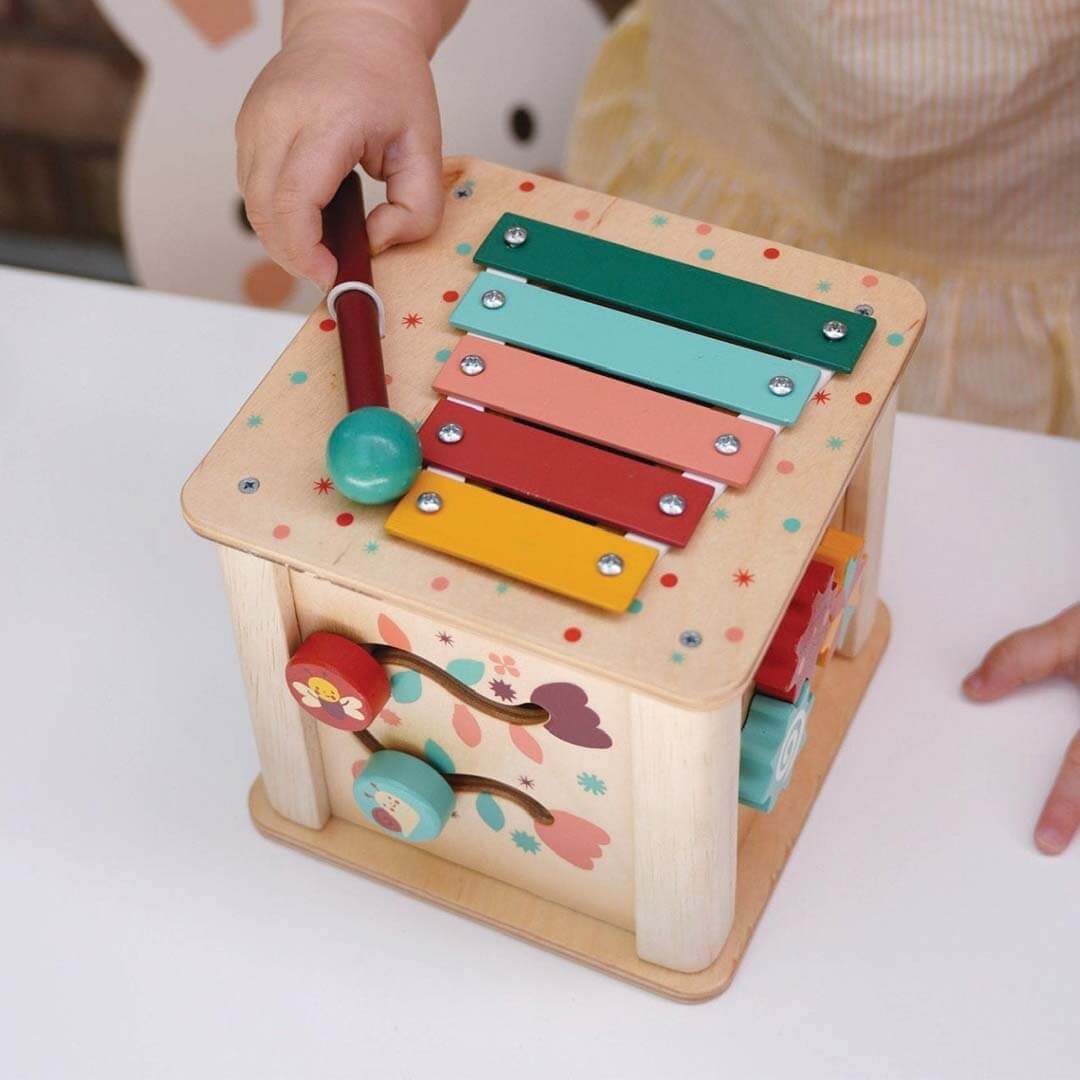 Colorful wooden toy with various interactive elements on a white surface.
