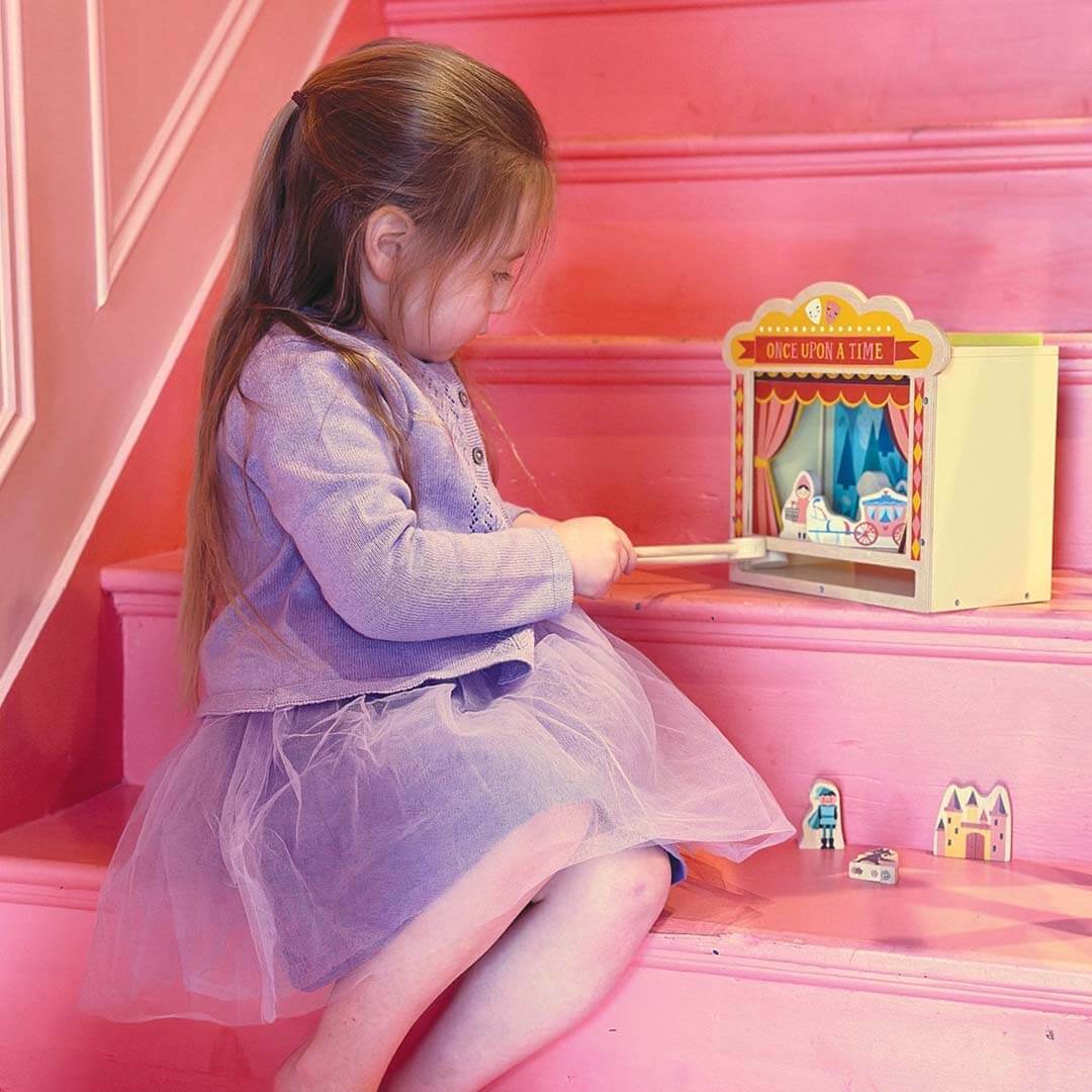 Child playing with a toy theater in a pink room