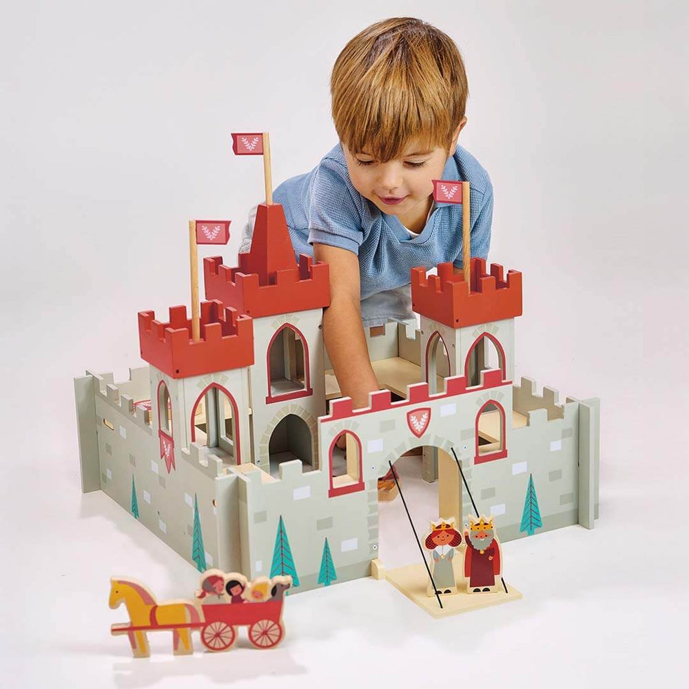 Child playing with a toy castle set on a white background