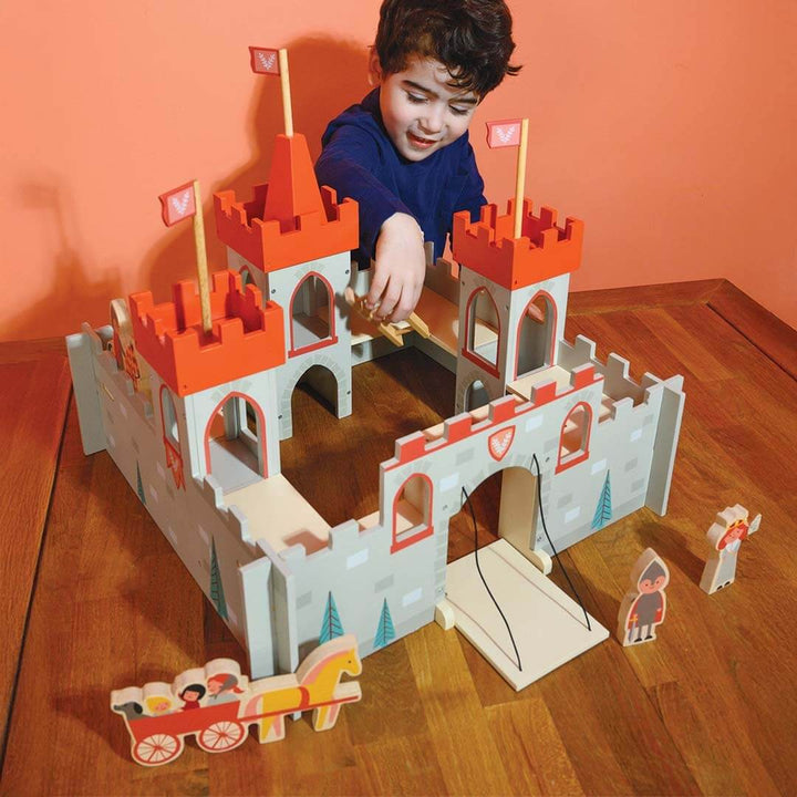 Child playing with a toy castle on a wooden table