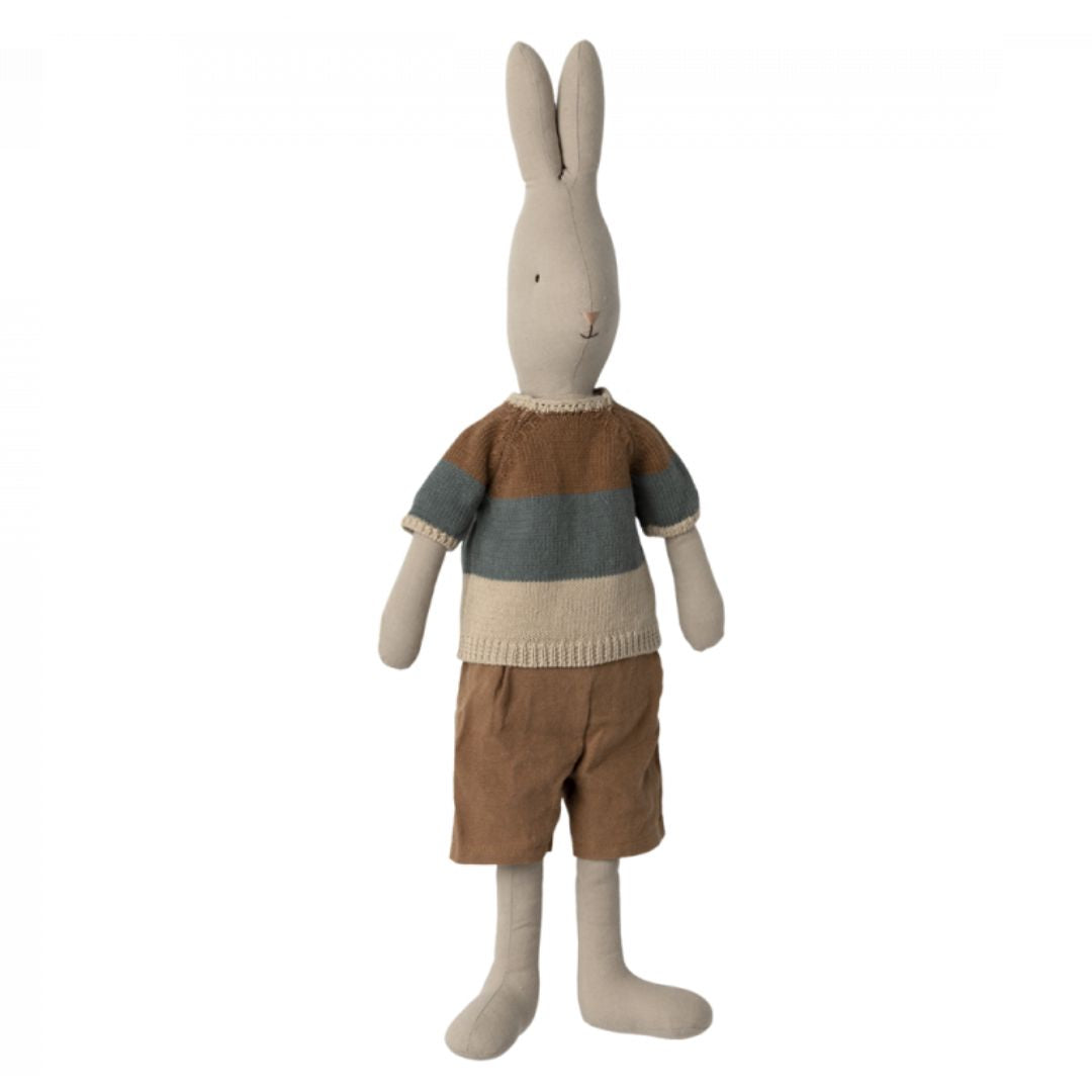 A white Maileg stuffed animal rabbit with a brown, grey and cream knit shirt and brown shorts on.