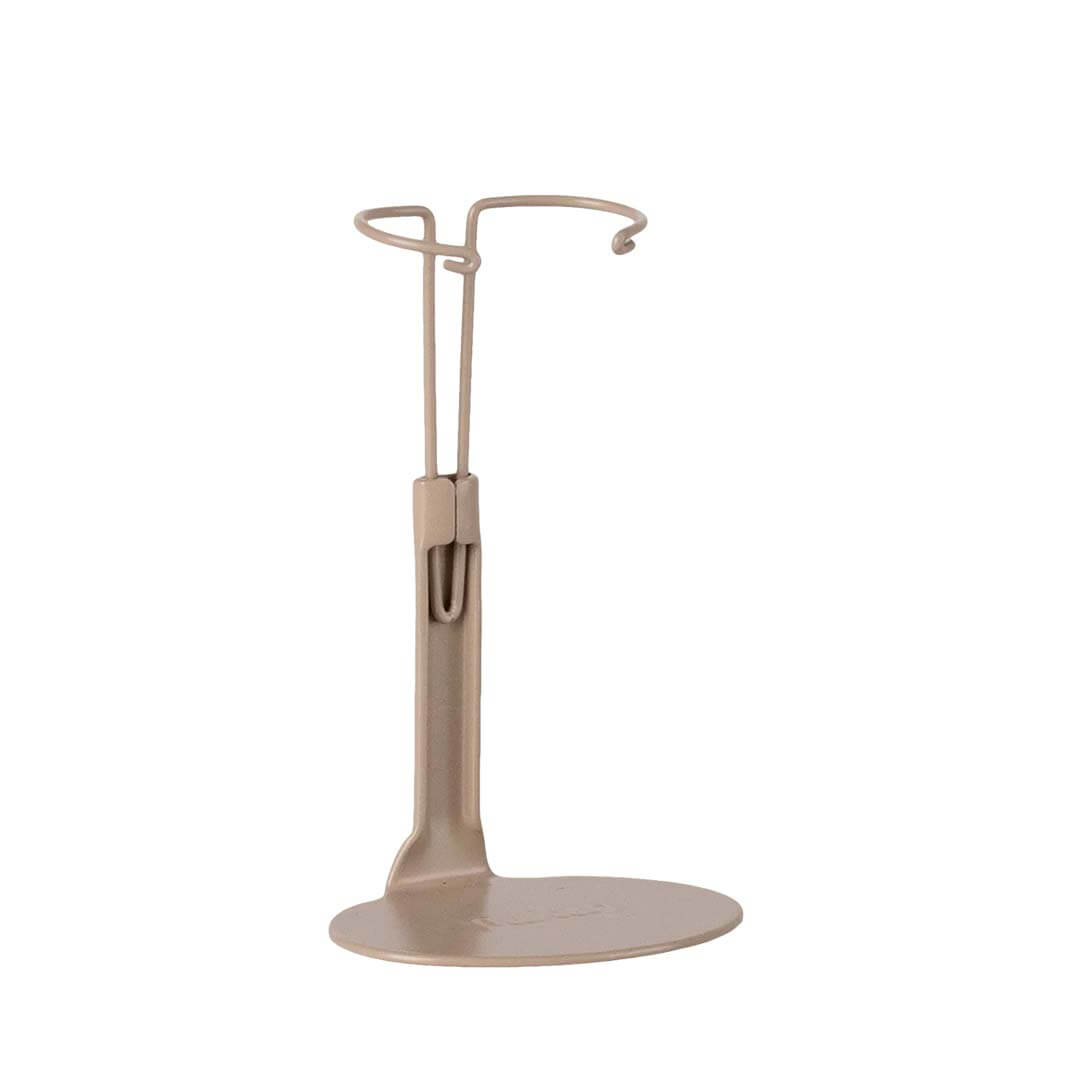A minimalist metal hook stand in a warm beige finish, featuring a flat circular base and a curved top hook, shown against a solid white background.