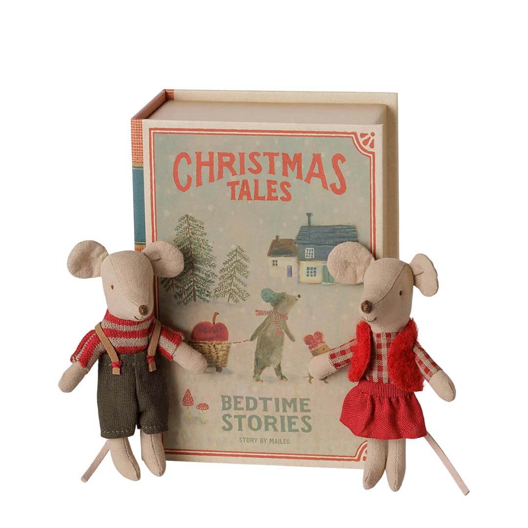A set of two small plush mouse toys dressed in holiday clothing, posed in front of a hardcover book titled "Christmas Tales" on a plain white background.
