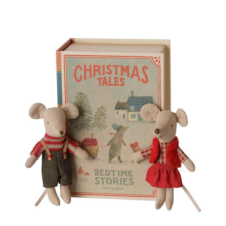 A set of two small plush mouse toys dressed in holiday clothing, posed in front of a hardcover book titled "Christmas Tales" on a plain white background.