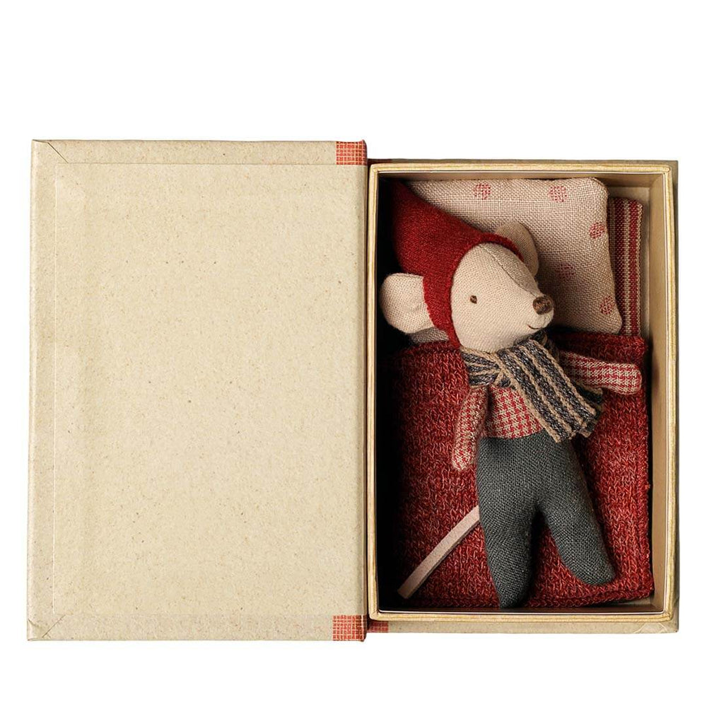 A small plush mouse toy dressed in a red hat and scarf with gray pants, presented inside an open kraft paper gift box with a matching pillow on a white background.