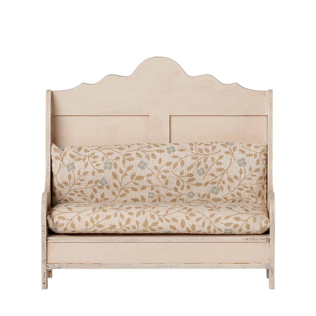 A small upholstered wooden daybed or bench for mice with a distressed cream finish, featuring a floral patterned cushion on a white background.