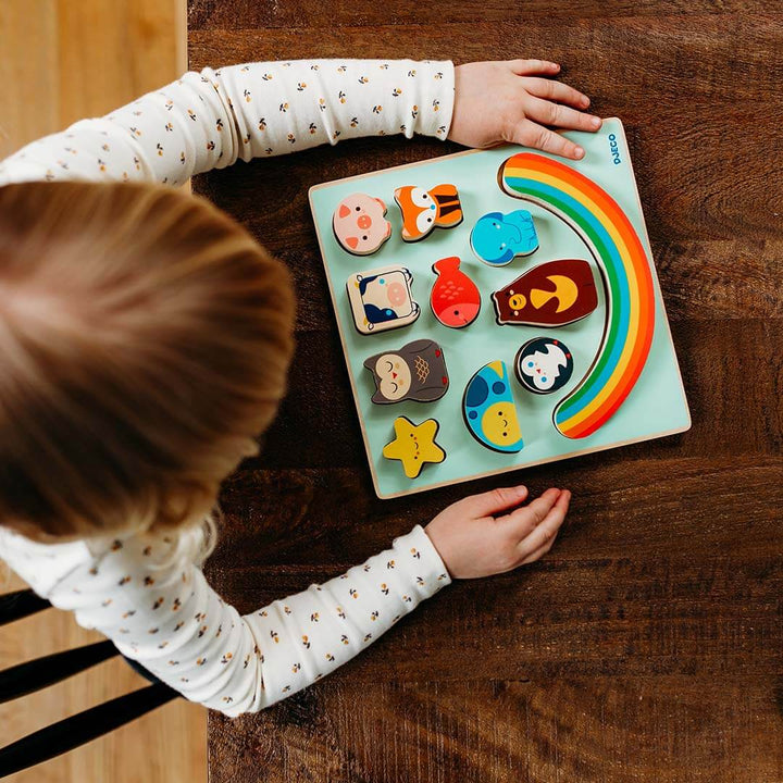 Puzz & Boom Animal Rainbow Wooden Puzzle on a wooden table with a childs hands.