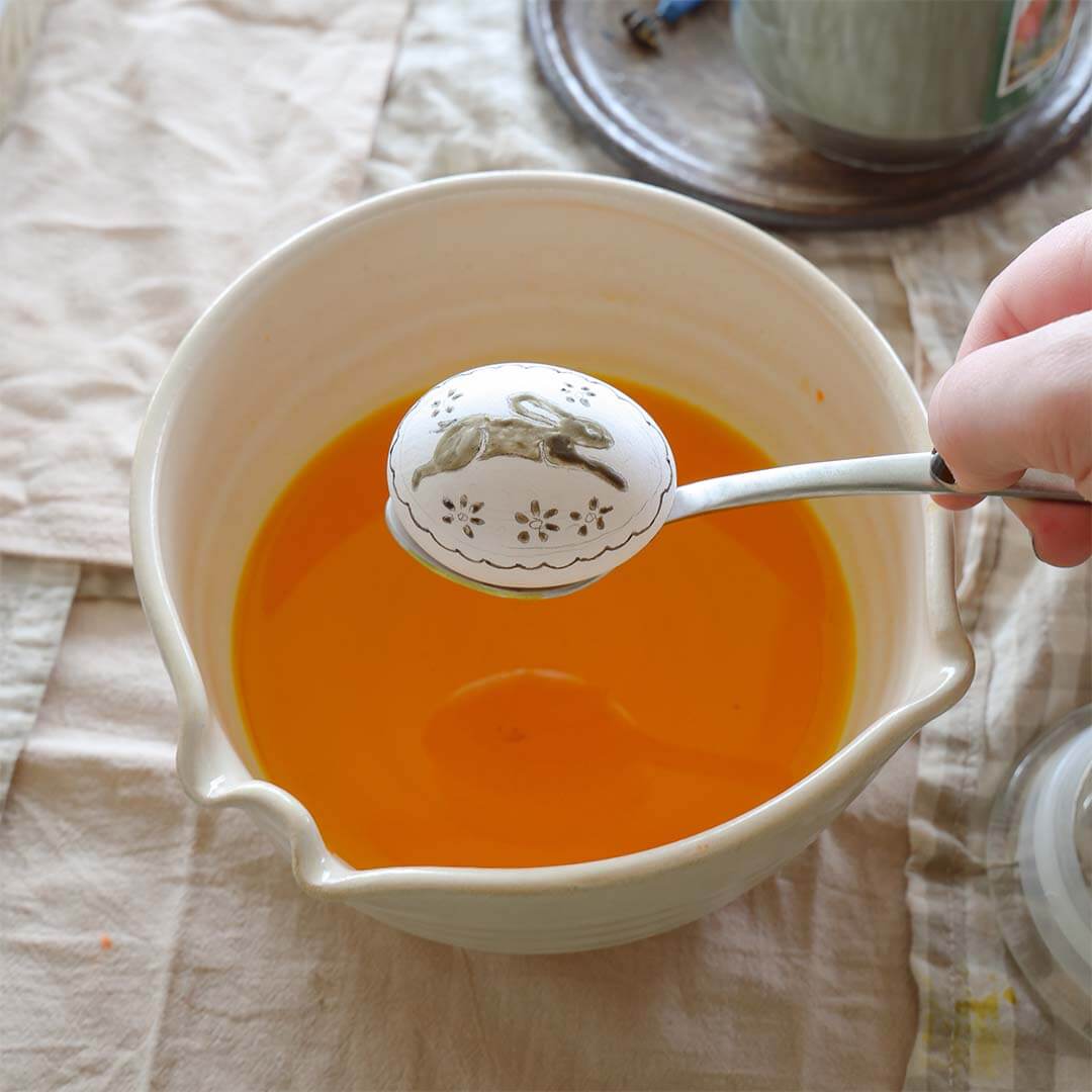 A Kid's Guide to Decorating Ukrainian Easter Eggs Kit being used with an egg to be dipped in dye.