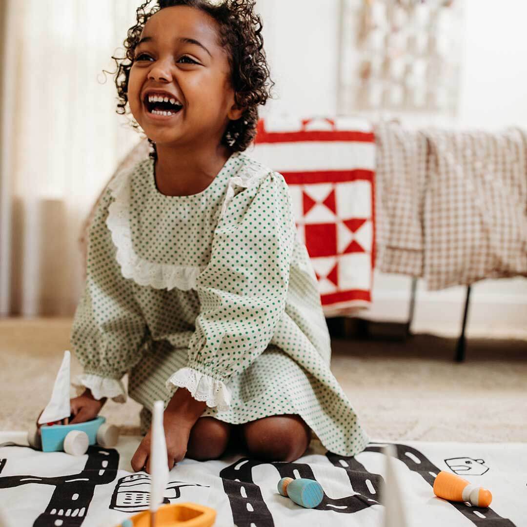 Child playing with toys on a blanket in a cozy room