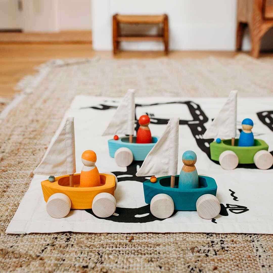 Wooden toy boats with colorful figures on a rug