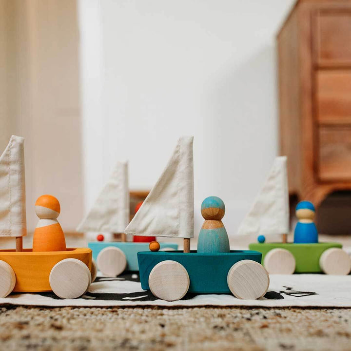 Set of colorful wooden toy sailboats on a neutral background