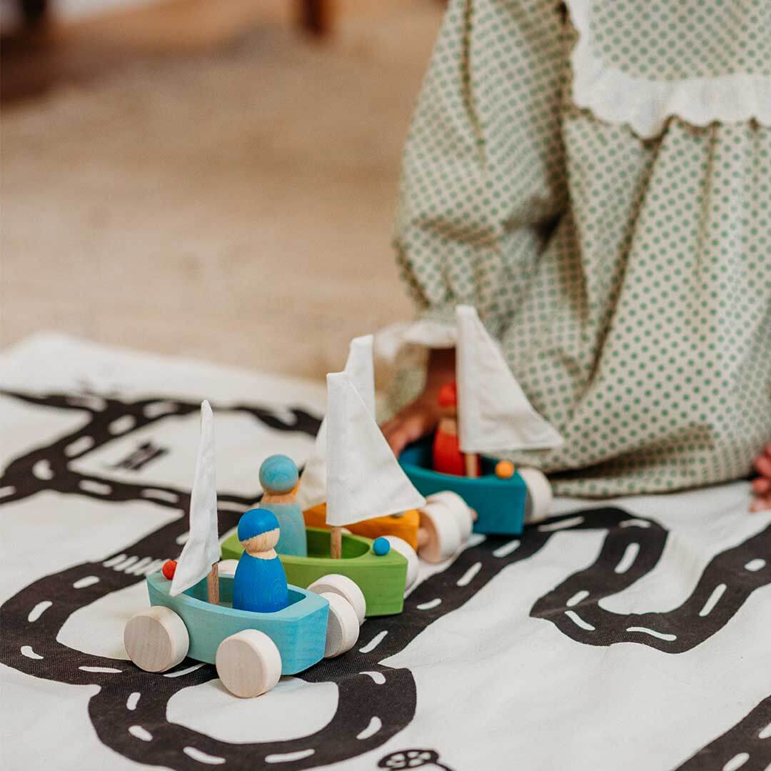 Children playing with wooden toy boats on a road mat