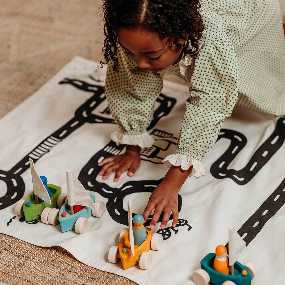 Child playing with wooden toys on a blanket with road prints