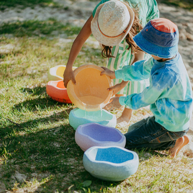 Two children pouring water from one  Stapelstein stepping stone to another.