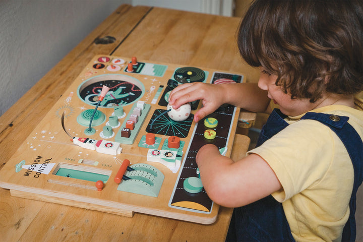 Boy playing with Tender Leaf Toys - Wooden Space Station on wooden table