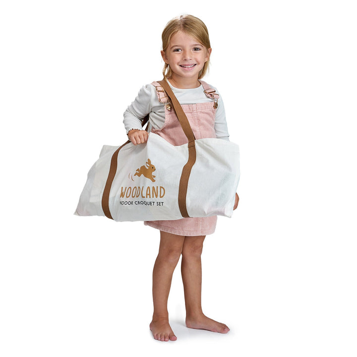 Girl holding Tender Leaf Toys Woodland Indoor Wooden Croquet Set bag