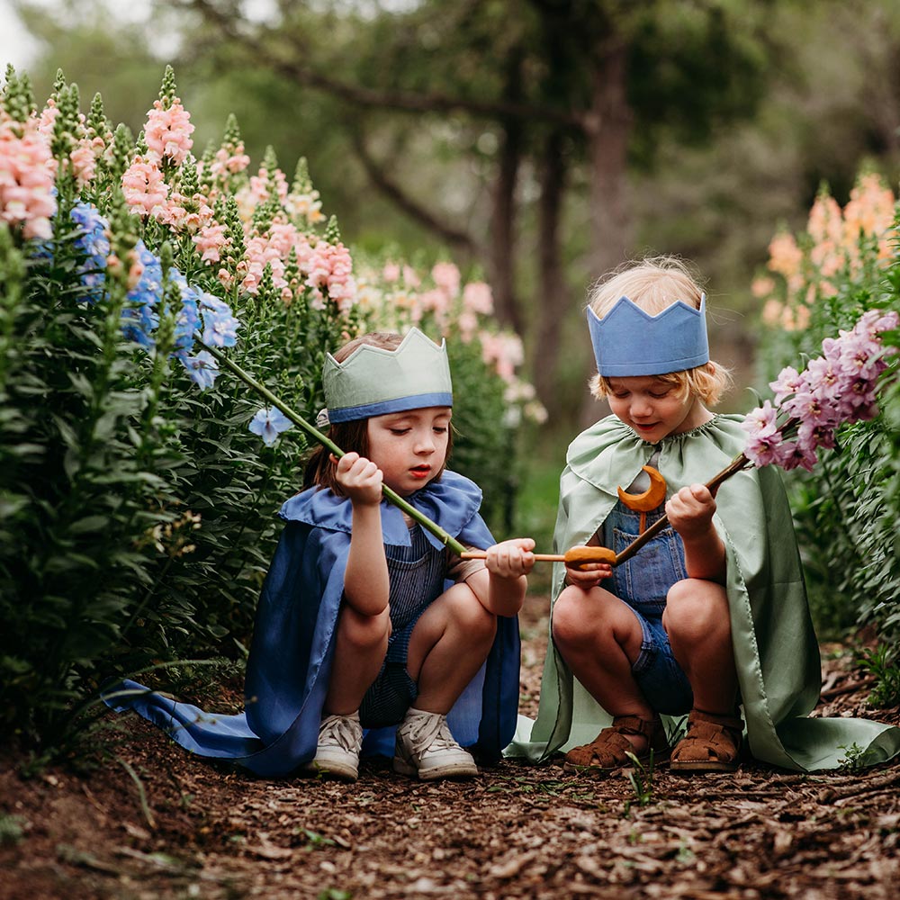 Child wearing Sarah's Silks Northern Coast Playsilk crown and cape in a flower field.