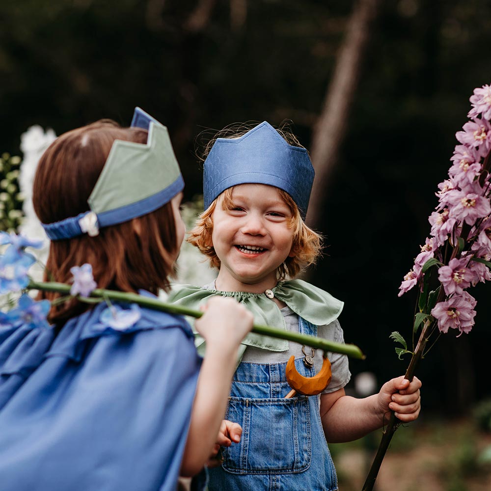 Child wearing Sarah's Silks Northern Coast Playsilk crown and cape in a flower field.