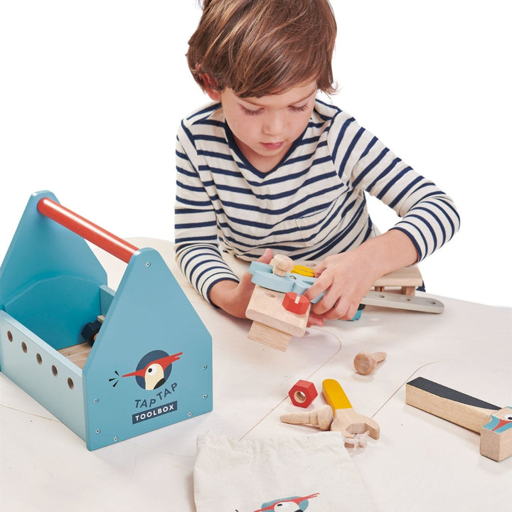 A child uses the tools from the Tender Leaf Toys Wooden Tap Tap Toolbox.