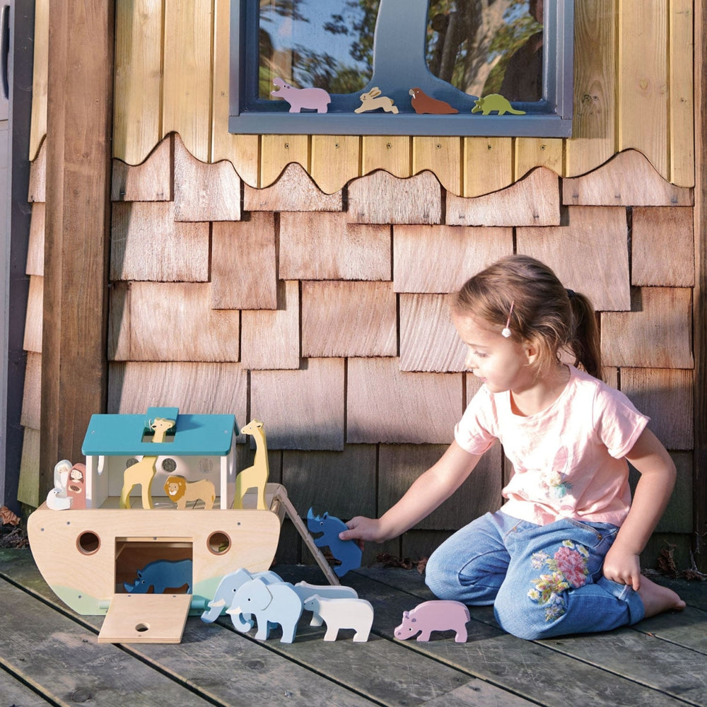 A young child playing with the wooden animal figures and Wooden Noah's Ark by Tender Leaf Toys.