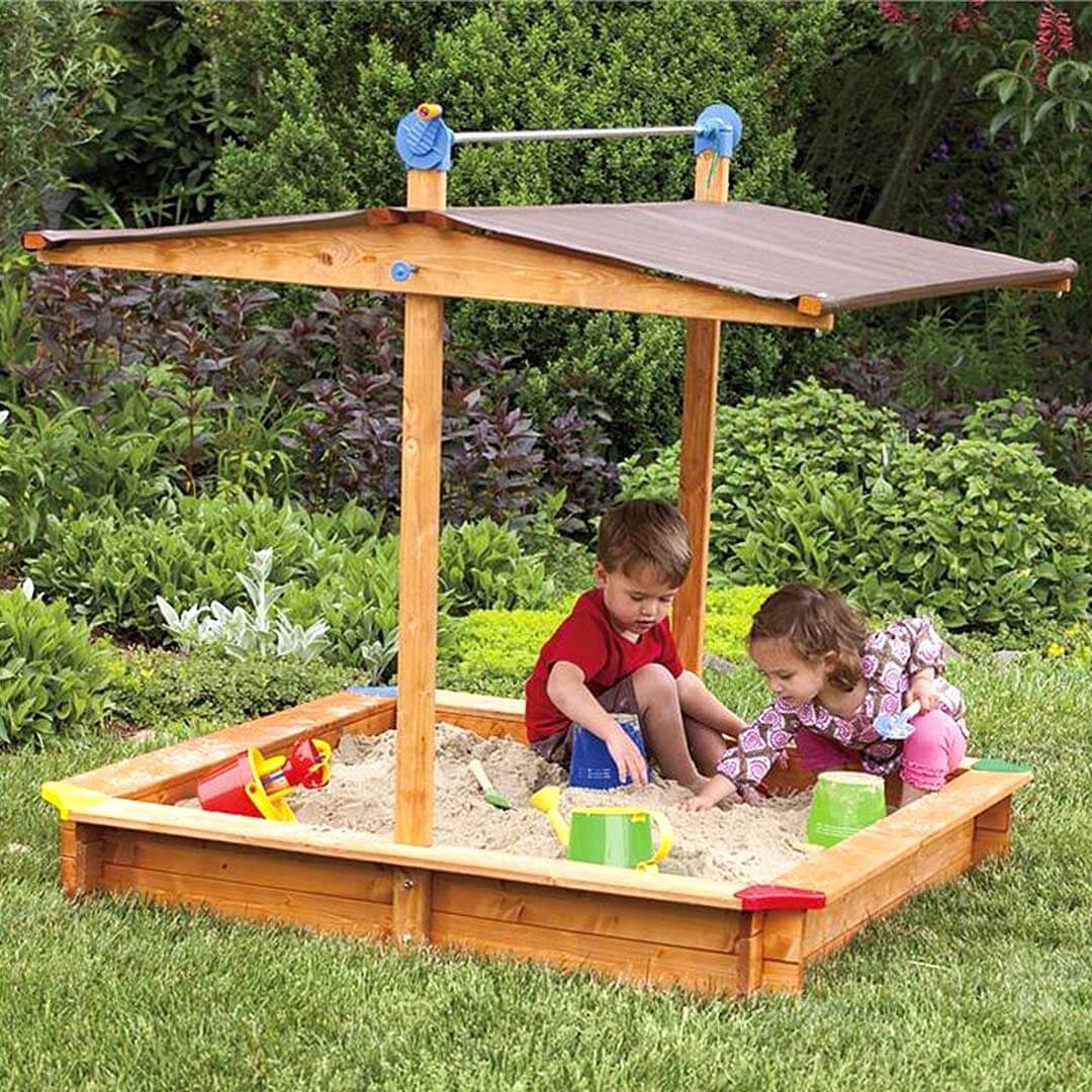 Kids Wooden Sandbox with Cover being played in outside by two kids.
