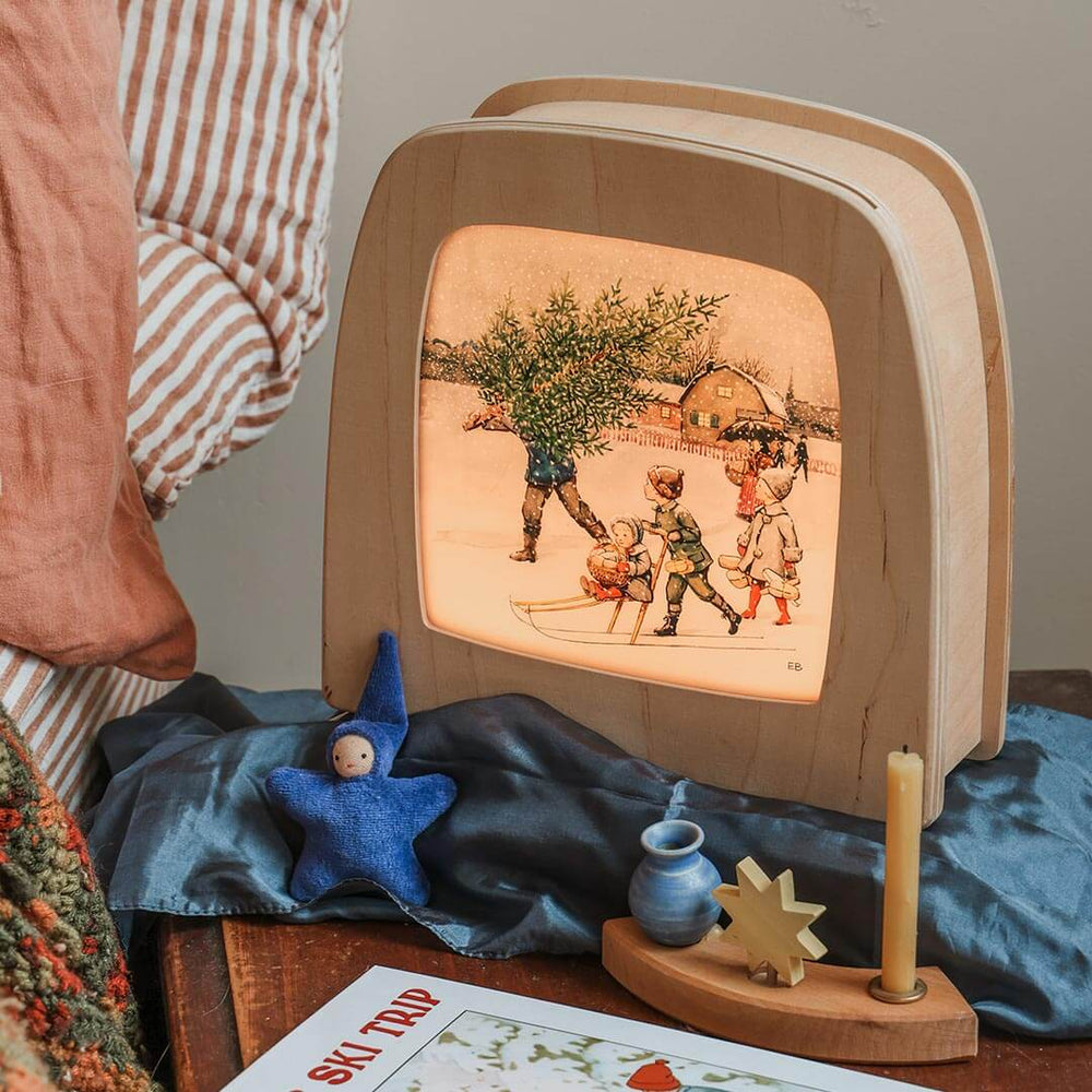 Wooden Toverlux lamp with illustrated cover on a table with decorative items