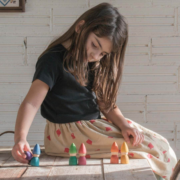 Young girl playing with colorful wooden blocks on a wooden floor.