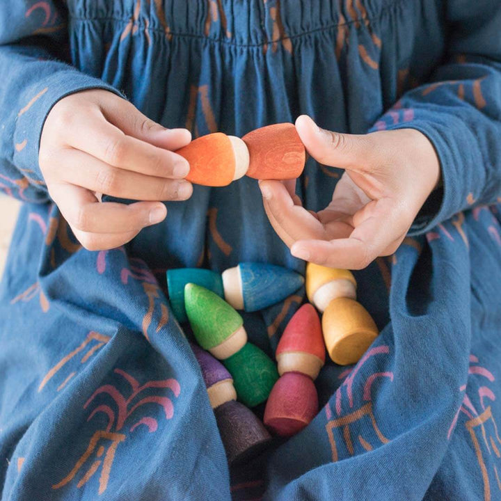 Child playing with colorful wooden toys in a blue dress.