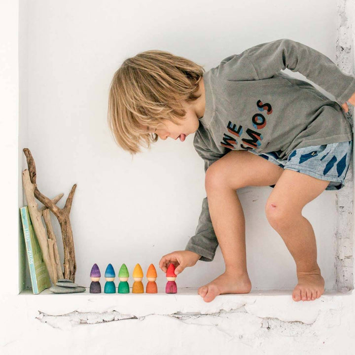 Child playing with colorful wooden toys on a white surface