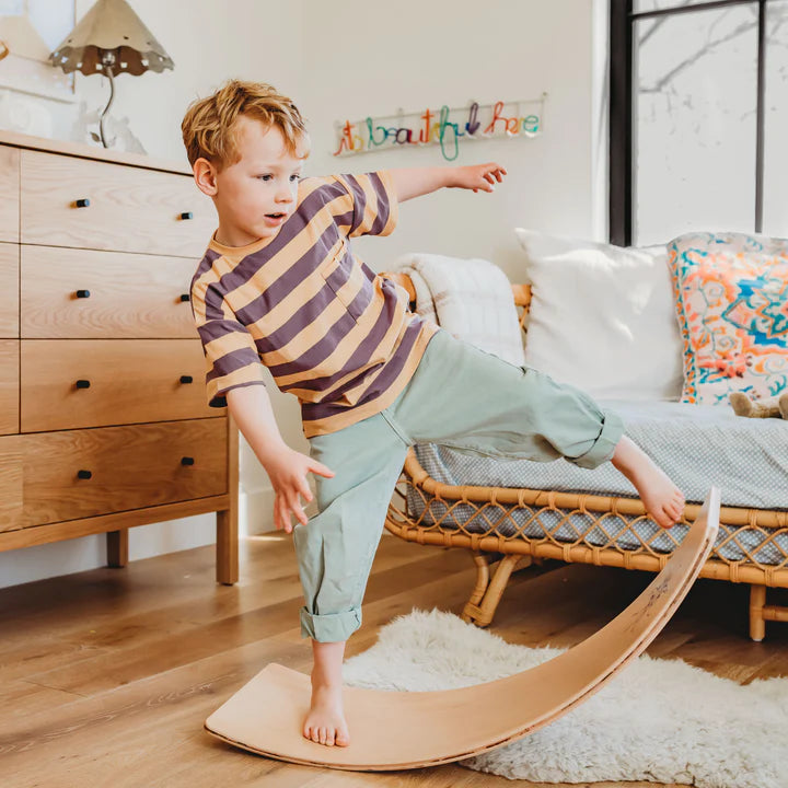 Child playing on a wooden rocker board