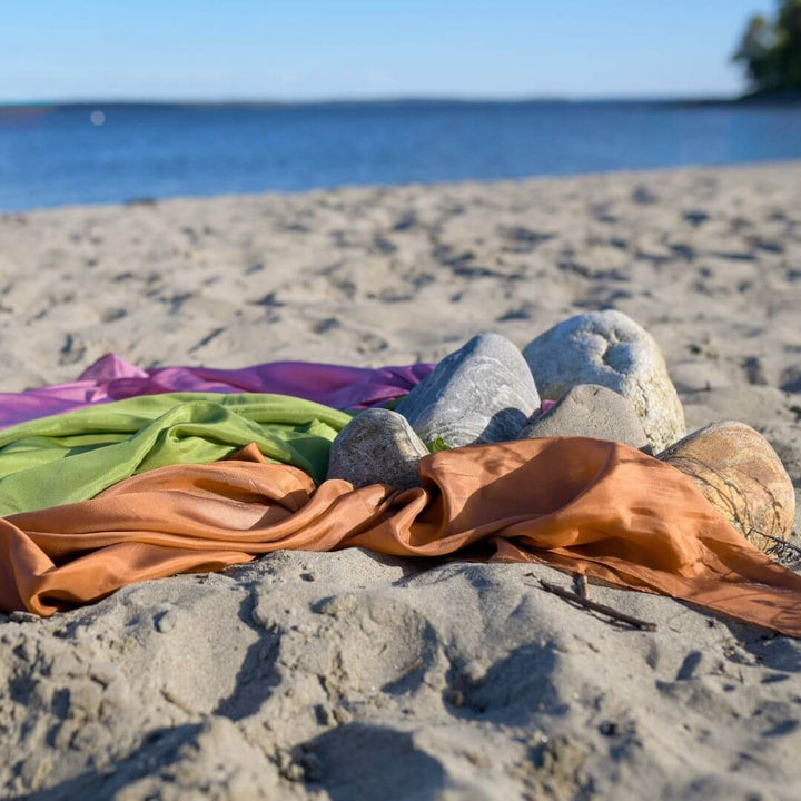 Three Bella Luna Toys Play Silks on a sandy beach.