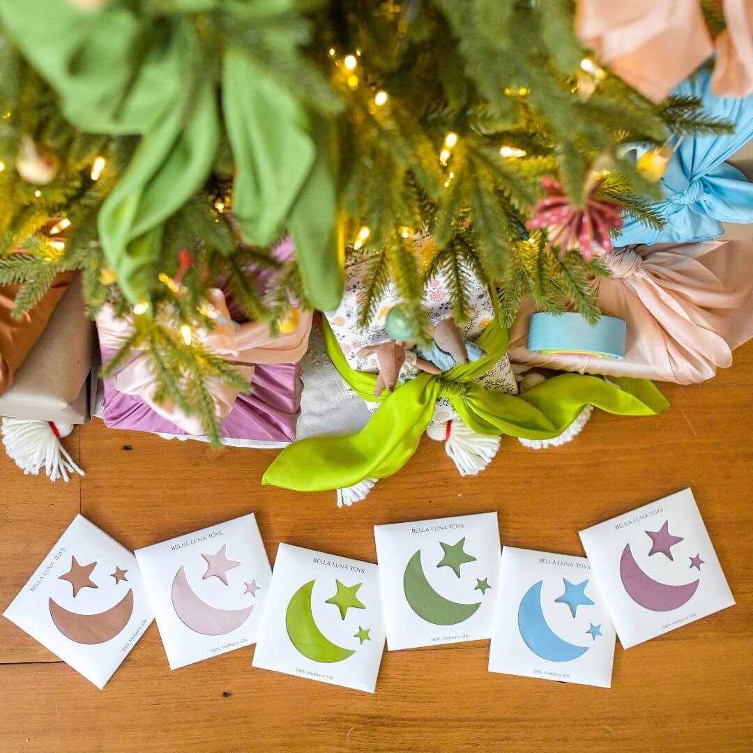 Bella Luna Toys Play Silks - Earth Mother collection spread out on a wooden floor in front of a Christmas tree.