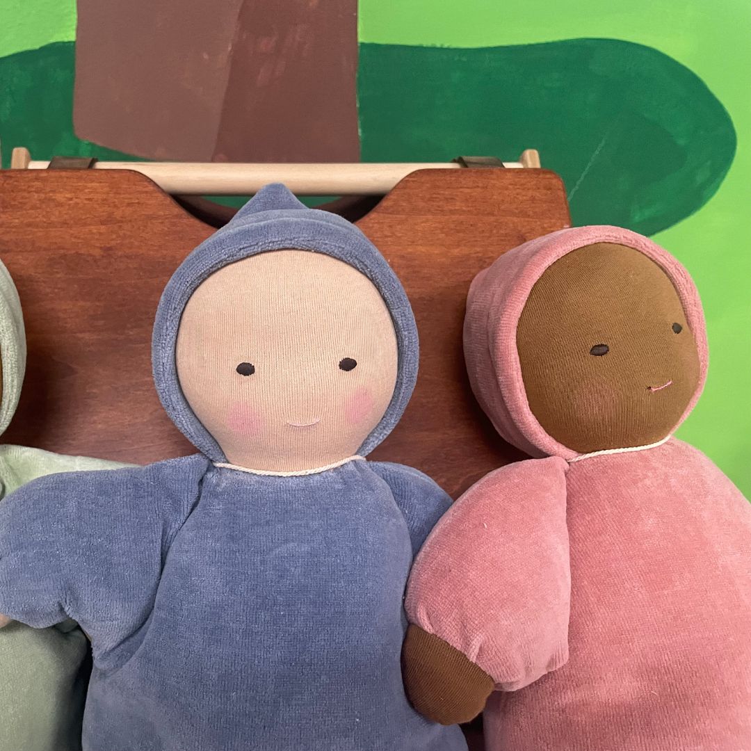 Two plush dolls, one in blue and one in pink, with a green background.