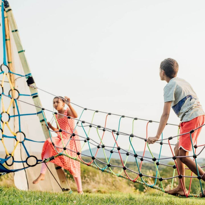 Two children climbing and balancing on the Bijou Rambler Rope Bridge during outdoor play - Bella Luna Toys