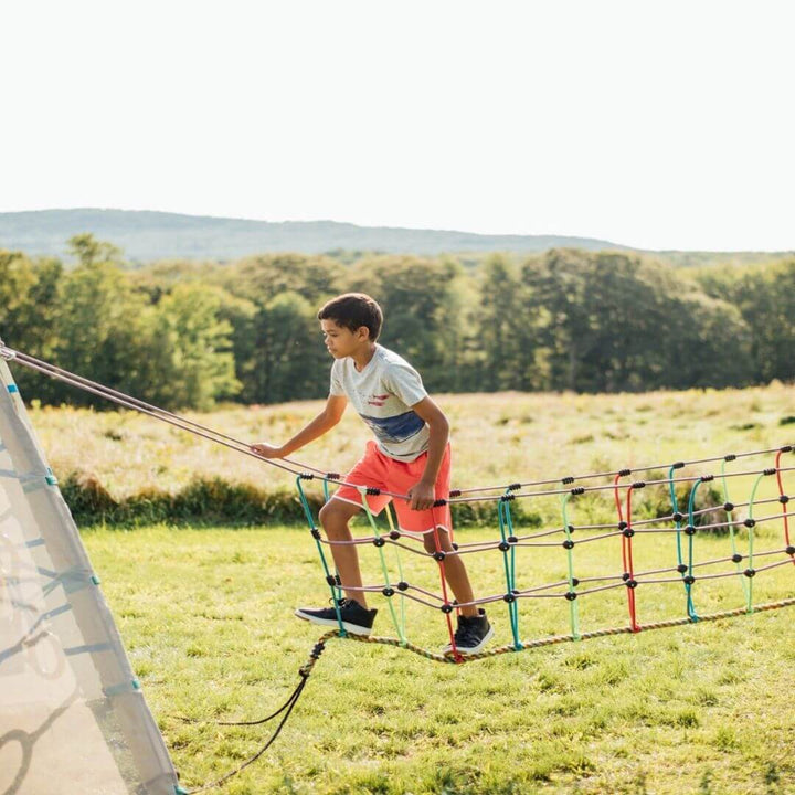 A child climbing and balancing on the Bijou Rambler Rope Bridge during outdoor play - Bella Luna Toys