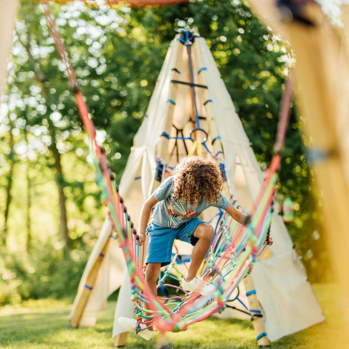 A child climbing and balancing on the Bijou Rambler Rope Bridge during outdoor play - Bella Luna Toys