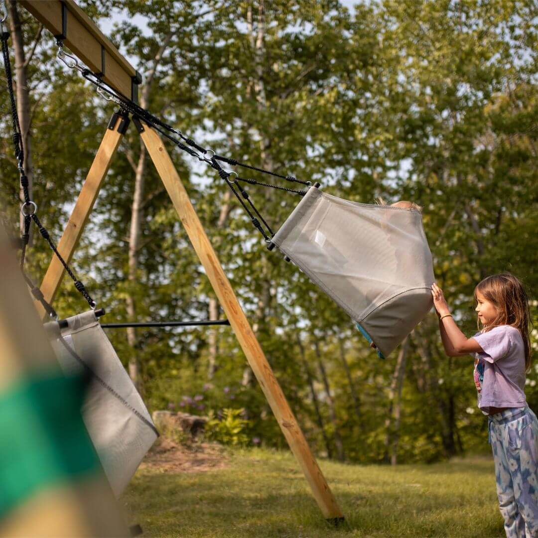 A child pushing her doll in the Bijou Sway swing.