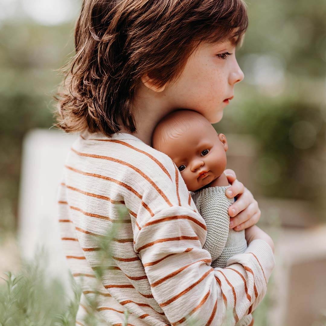 A child is holding a realistic baby doll.