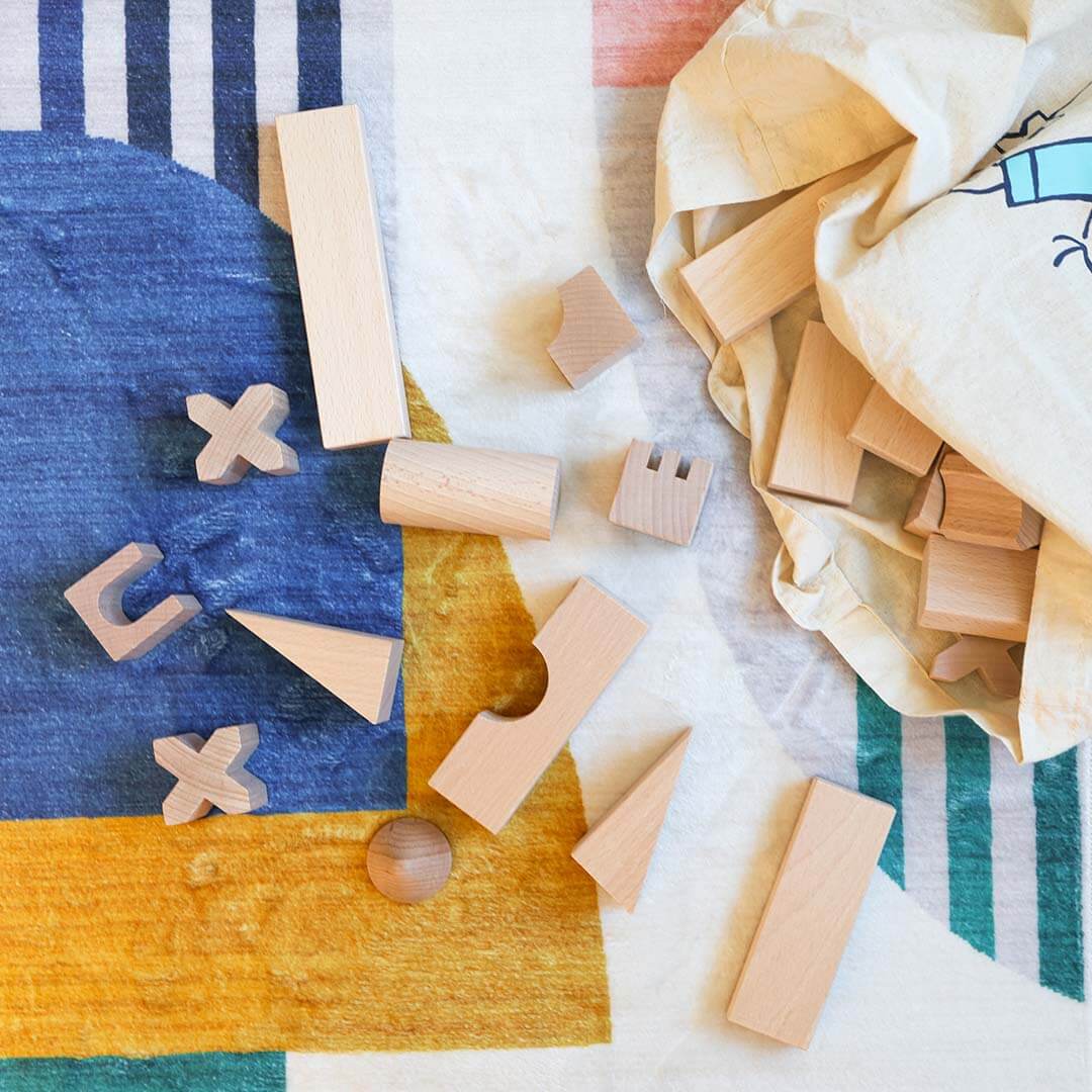 A bunch of wooden blocks are on a colorful rug.