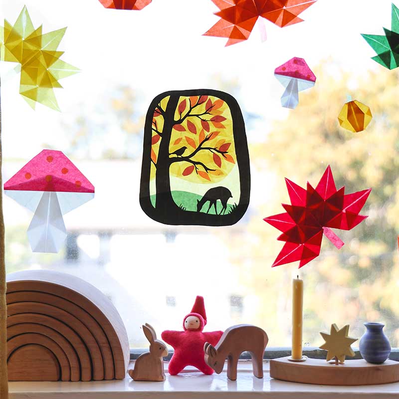 Decorative window stickers with autumn design and colorful geometric shapes on a blurred indoor background.