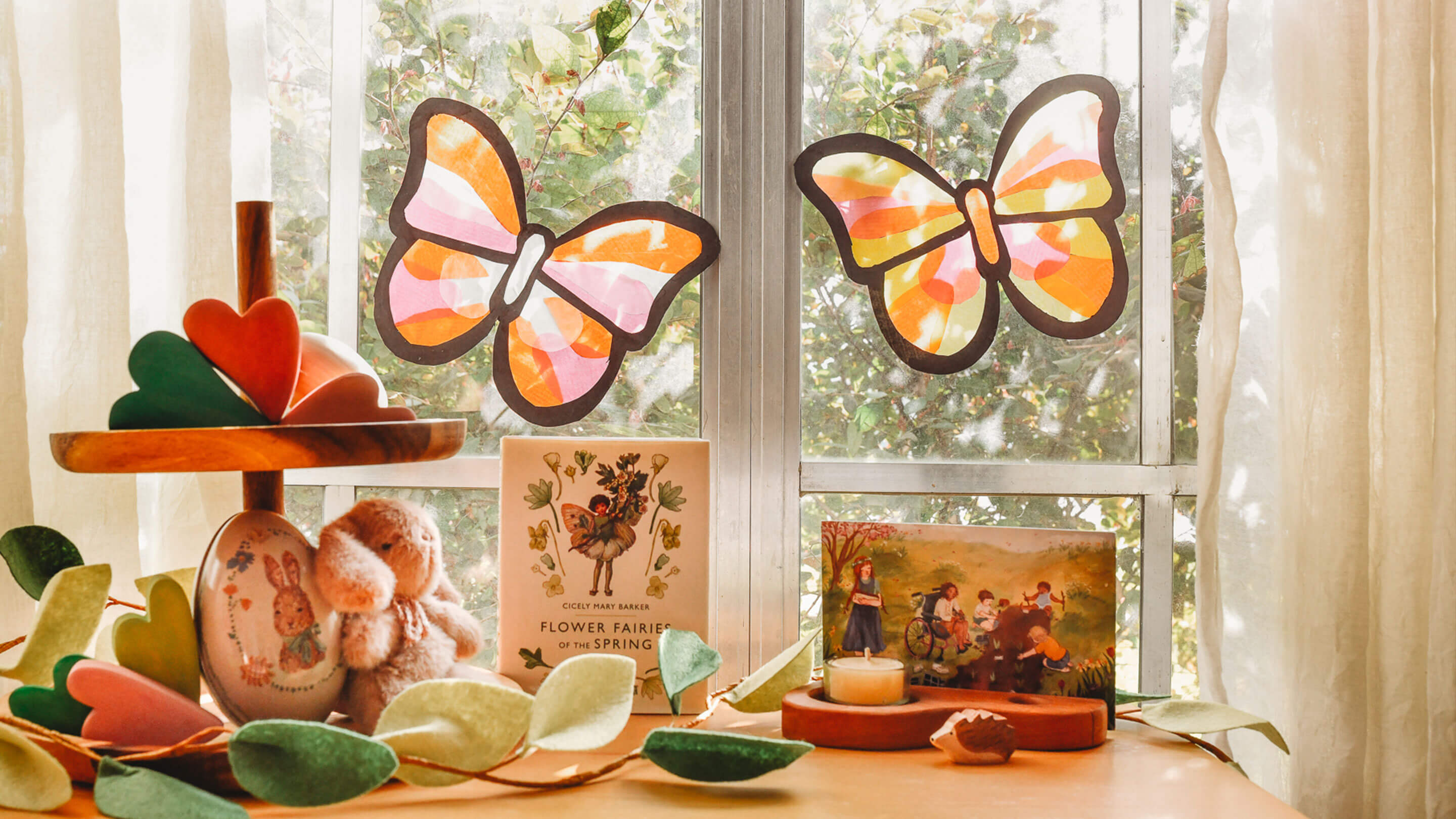 Butterfly decorations on a window sill with a book and small figurines.