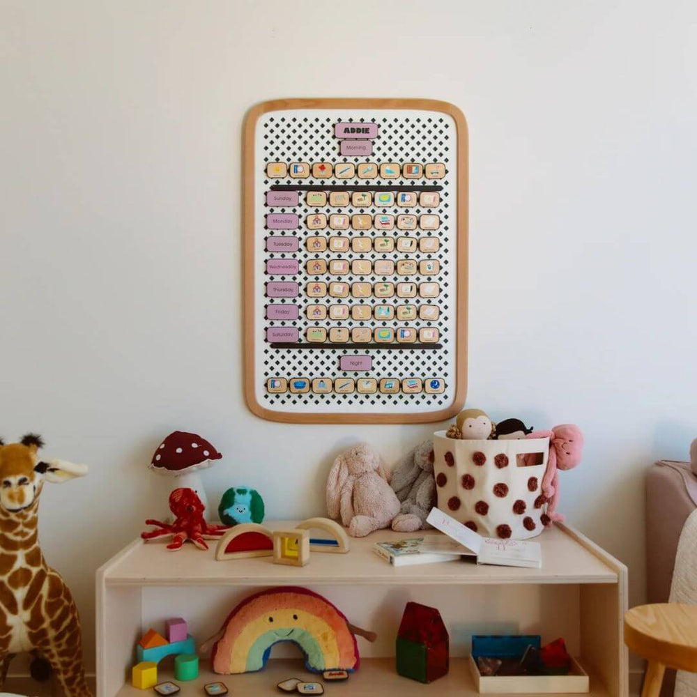 Children's room with a shelf displaying toys and a colorful  Charmspring routine board on the wall.