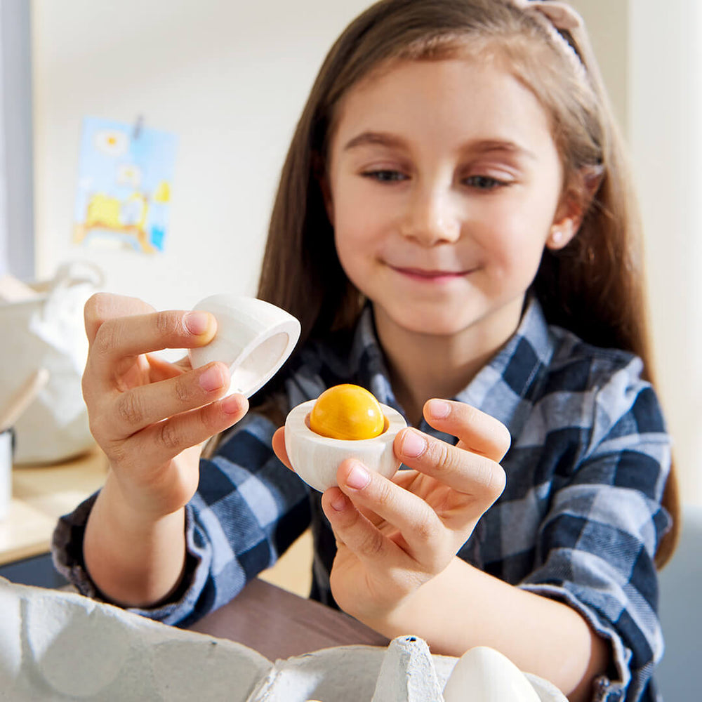 Child holding a Creative Play – Wooden Eggs Play Food Set toy egg with a removable yellow yolk.